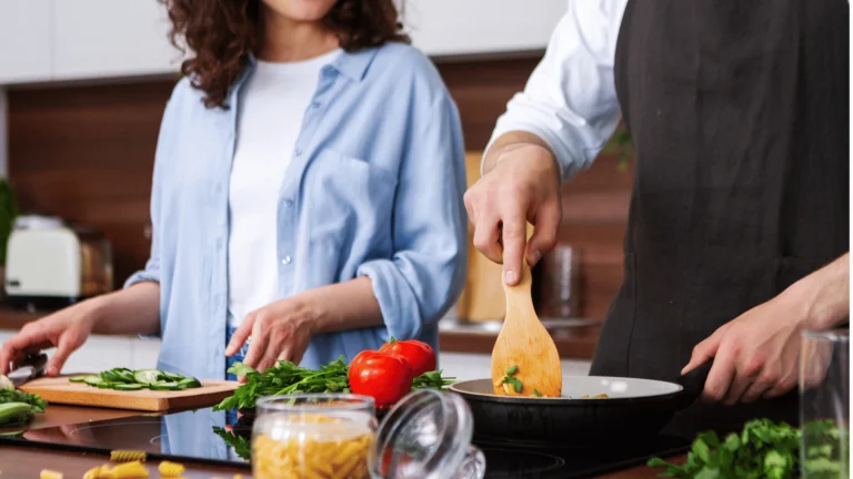 زوجان يحضّران الخضار والمكرونة في المطبخ – Y-Needs